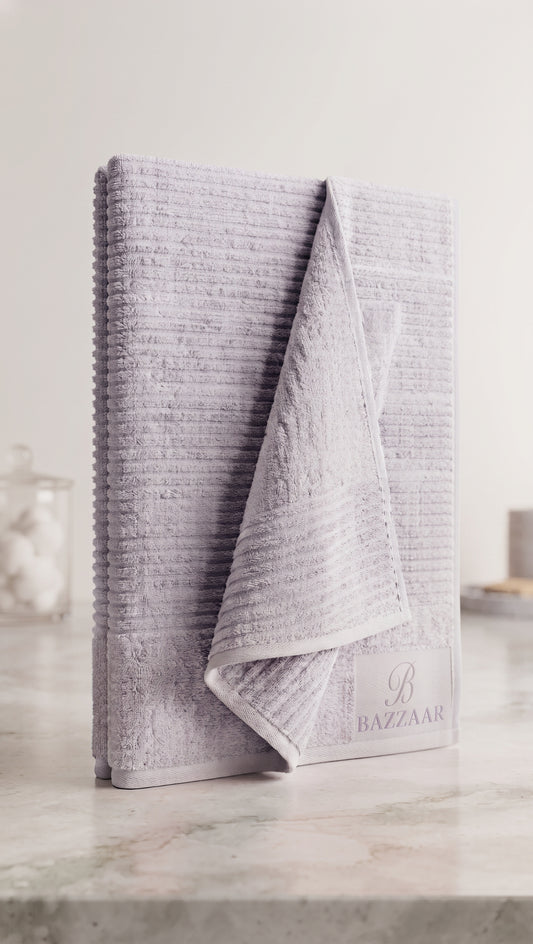 Light grey textured towel with horizontal raised lines, folded upright with Bazzaar branding visible
