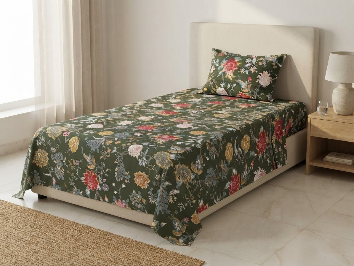 Olive green bedsheet with red, pink, cream and yellow floral vines, displayed with a coordinating pillow on a cream upholstered bed.