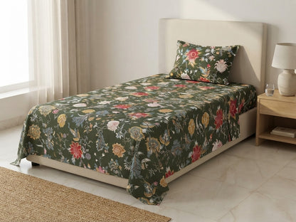 Olive green bedsheet with red, pink, cream and yellow floral vines, displayed with a coordinating pillow on a cream upholstered bed.