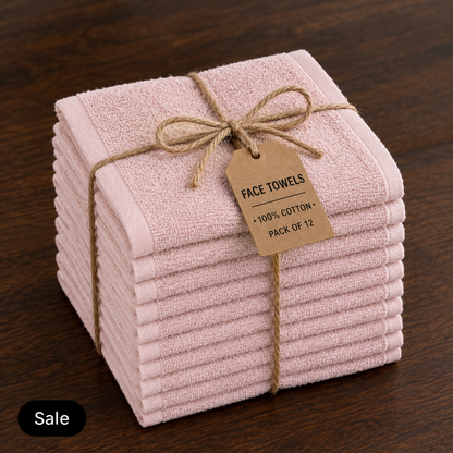 Stack of twelve pale pink cotton face towels tied with twine and a label stating 100% cotton, pack of 12