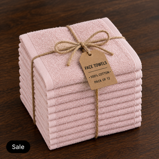 Stack of twelve pale pink cotton face towels tied with twine and a label stating 100% cotton, pack of 12